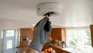 Hand replacing battery in ceiling smoke detector