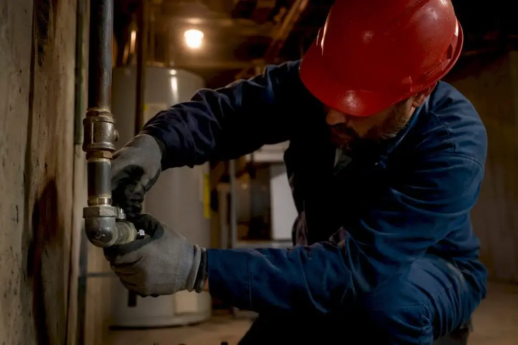 Technician inspecting gas line valve in basement