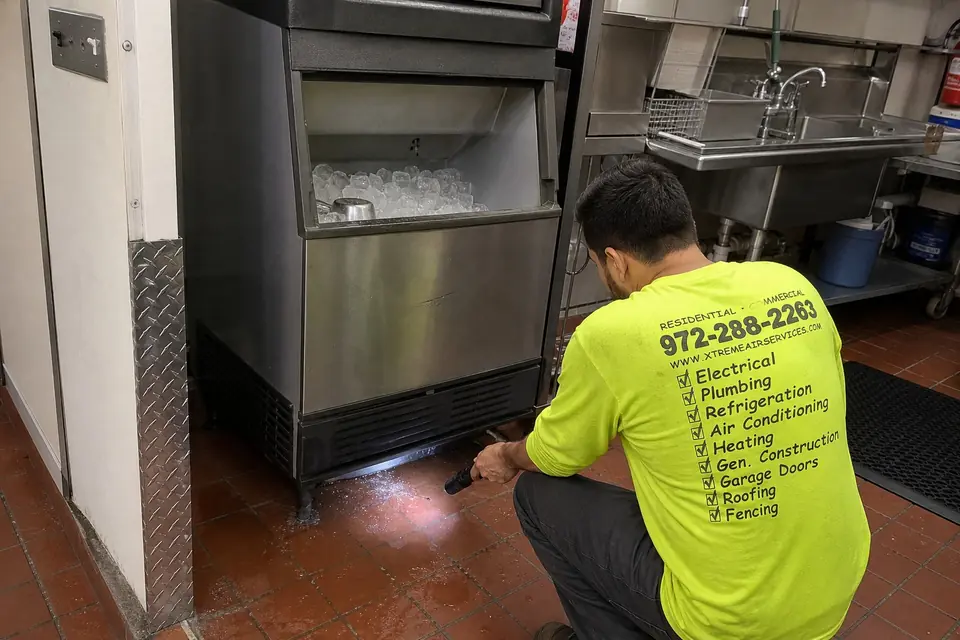 Signs a Commercial Ice Machine Needs a Repair Call, Sunnyvale, TX Technician inspecting the base of a commercial ice machine with a flashlight, Sunnyvale, TX